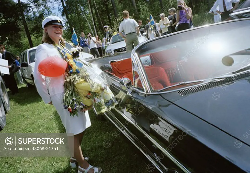 Female high school student standing by veteran car, Sweden.