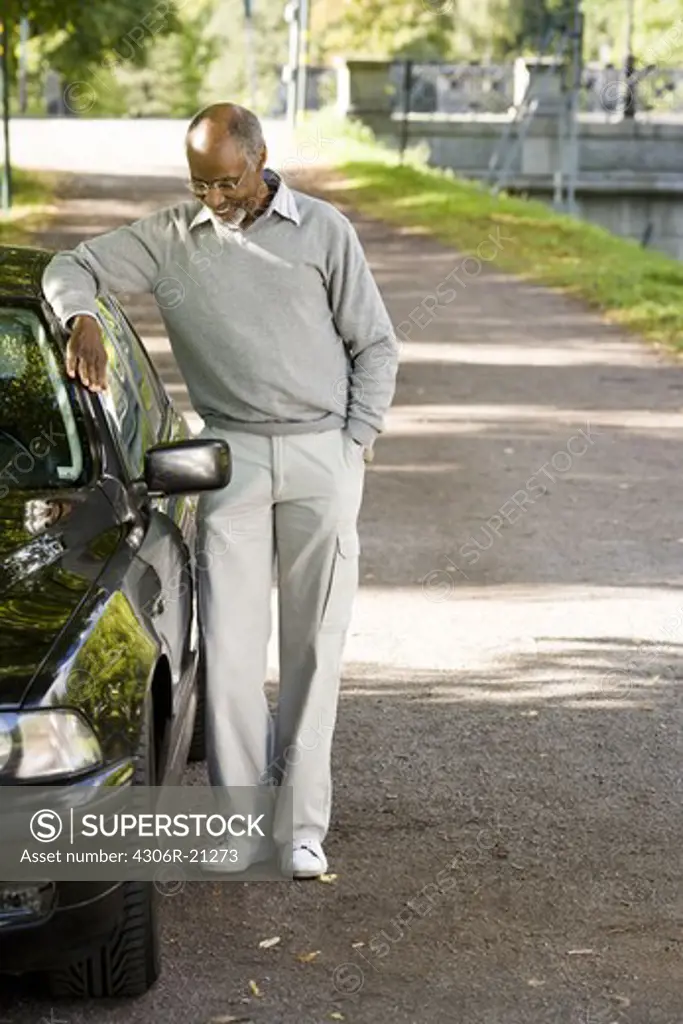 Senior man standing by a black car, Sweden.