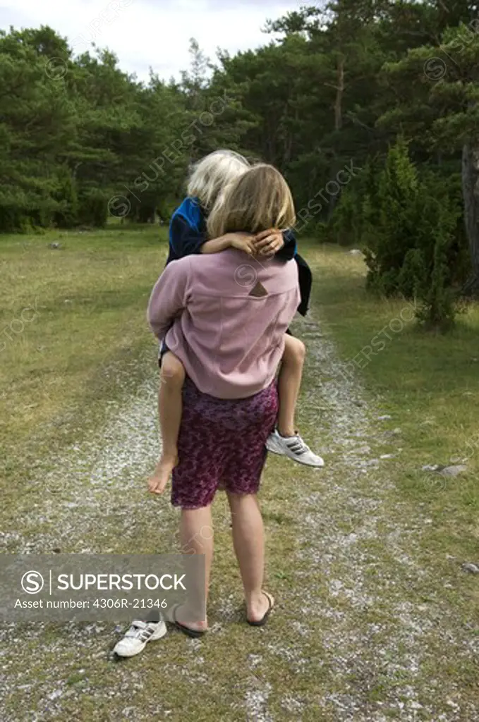 Mother holding son, standing on dirt road