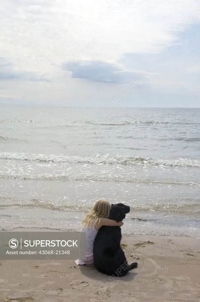 Girl with dog sitting on beach