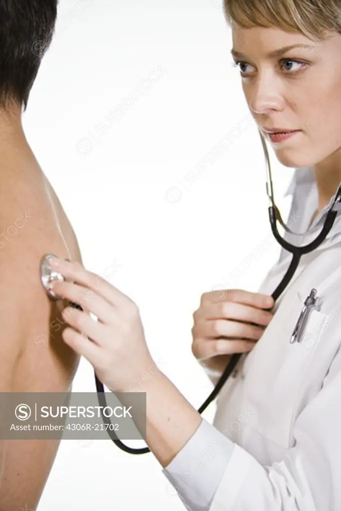 Female doctor using a stethoscope at a male patient, Sweden.