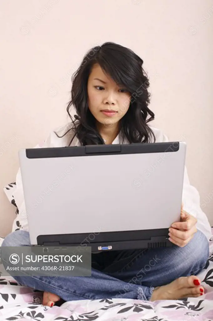 Woman in a bed using a laptop, Sweden.