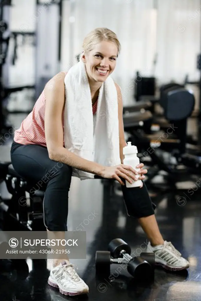 A woman with a water bottle at a gym, Sweden.