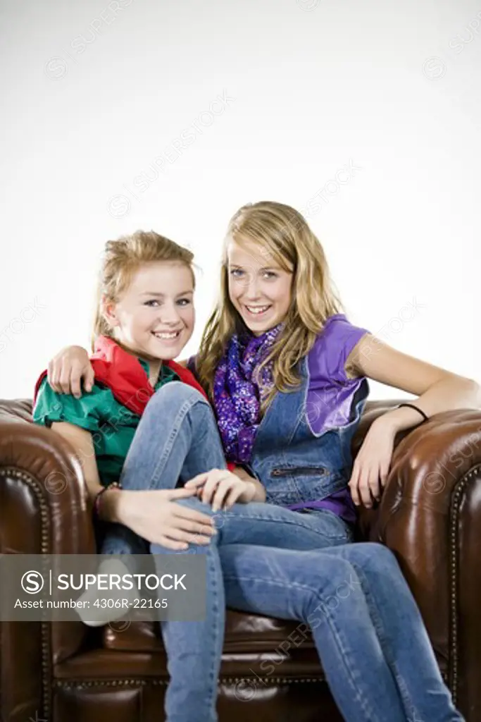 Two teenager girls in a armchair.