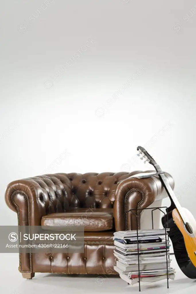 An armchair, newspapers and a guitar.