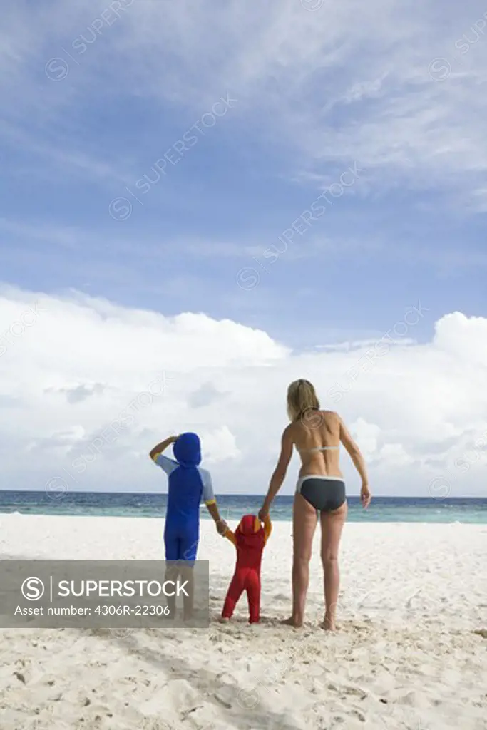 Mother walking on a beach with her two children, the Maldives.