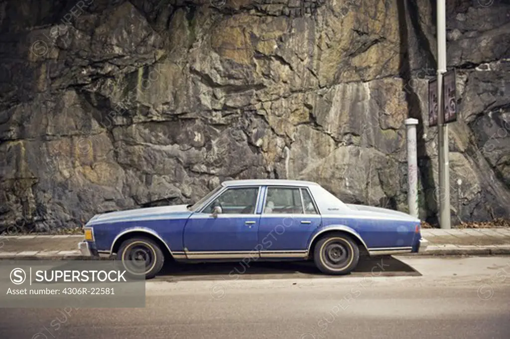 A blue car against a stone wall, Sweden.