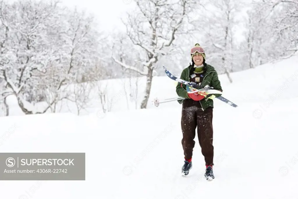 Woman carrying skis in a wintry landscape, Sweden.