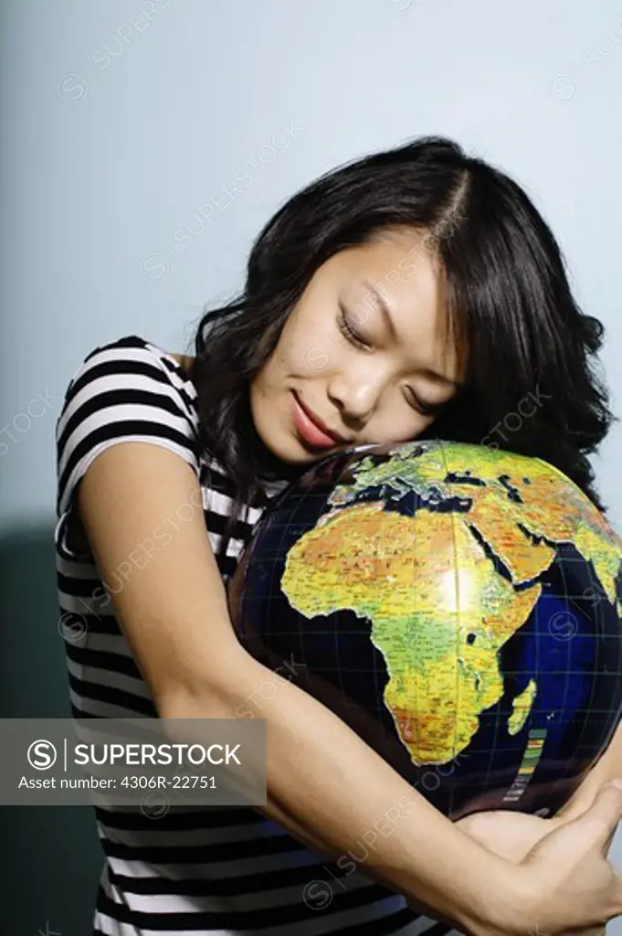 Asian woman hugging a terrestrial globe.