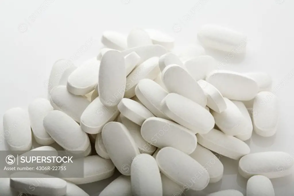 Heap of white pills on white surface