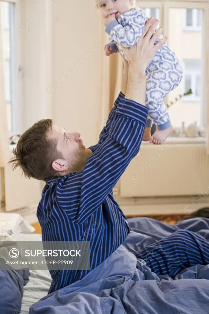 Father with his baby daughter in a bed, Sweden.