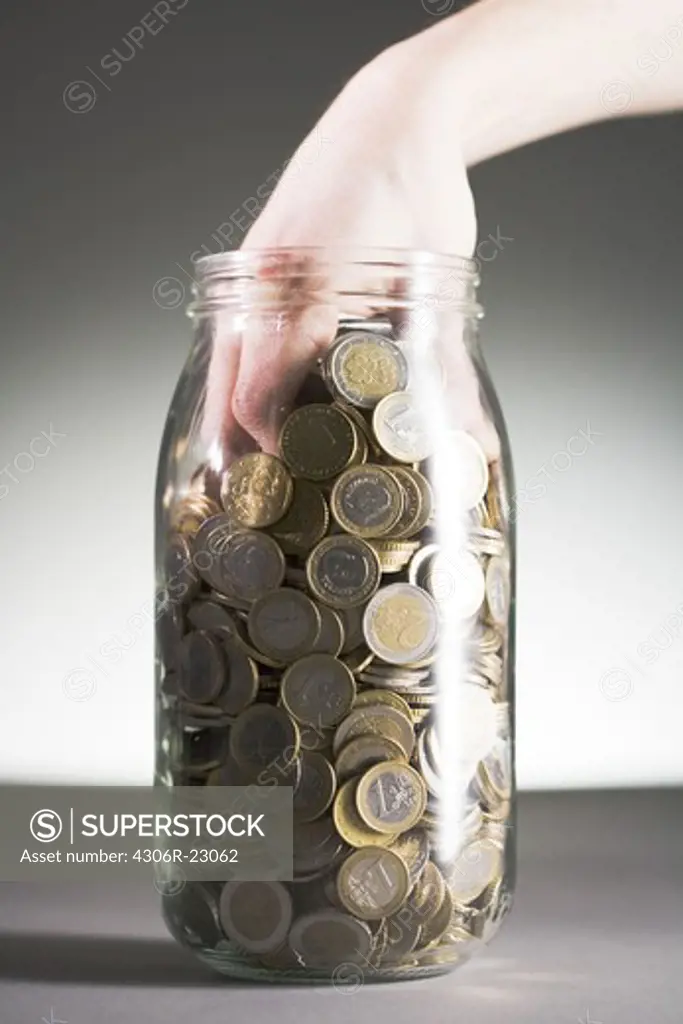 Euros in a jar against a gray background.