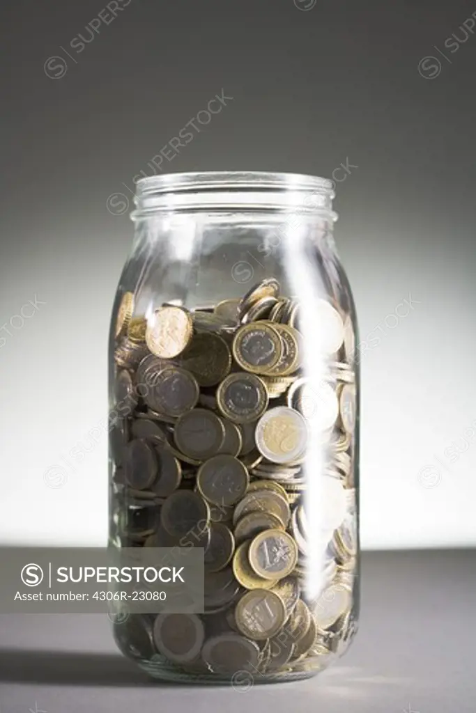 Euros in a jar against a gray background.