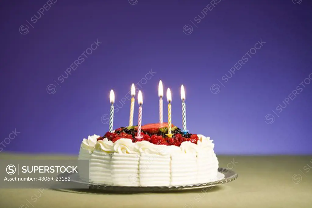 A cream  cake with lighted candles.