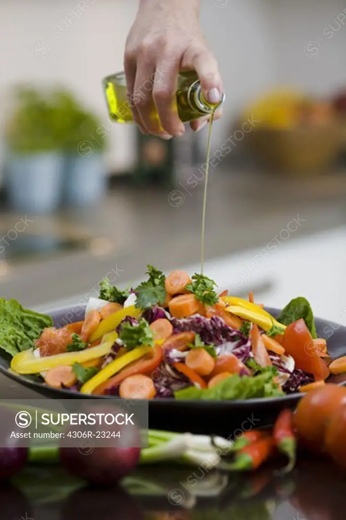 Woman pouring oil over vegetables, Sweden.