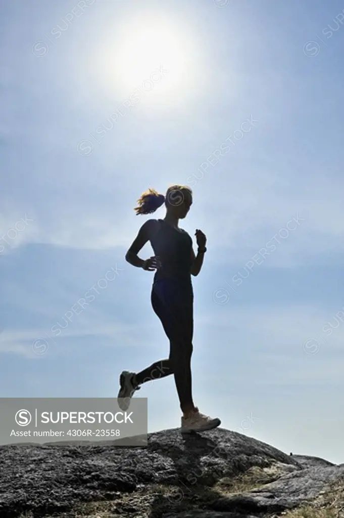 Young woman running against a blue sky, Sweden.