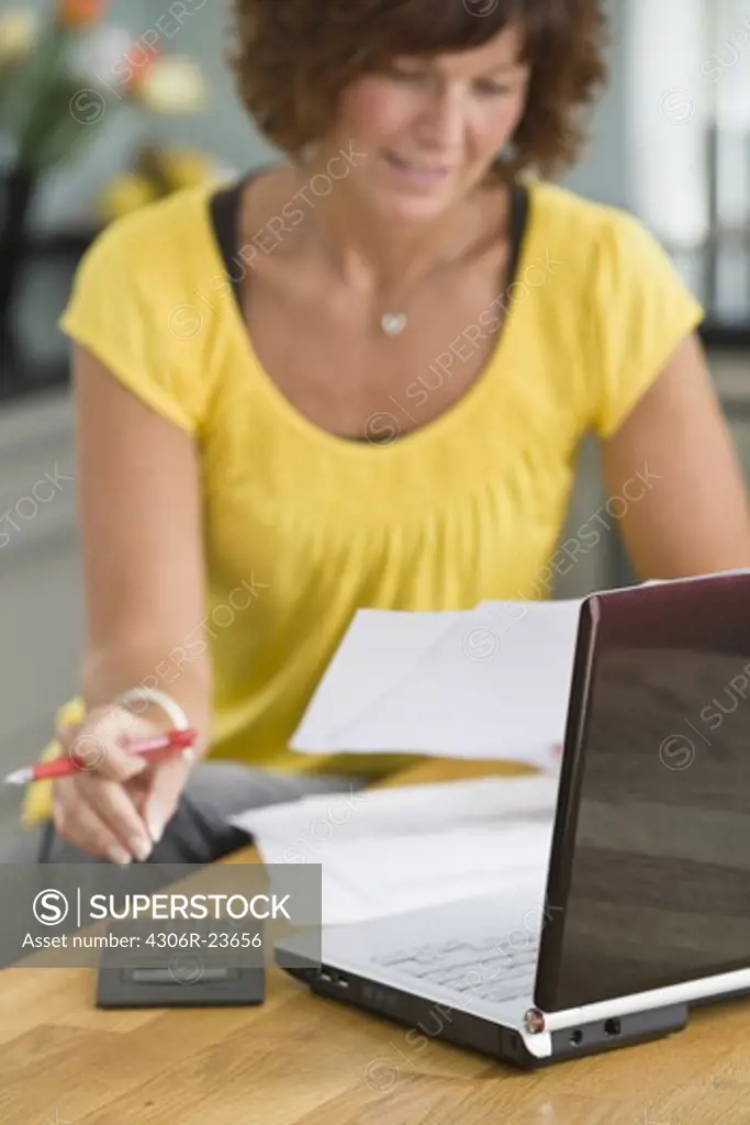 Woman sitting with laptop and bills