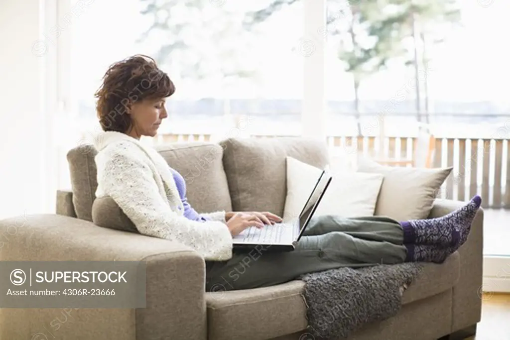 Woman sitting on sofa and surfing internet