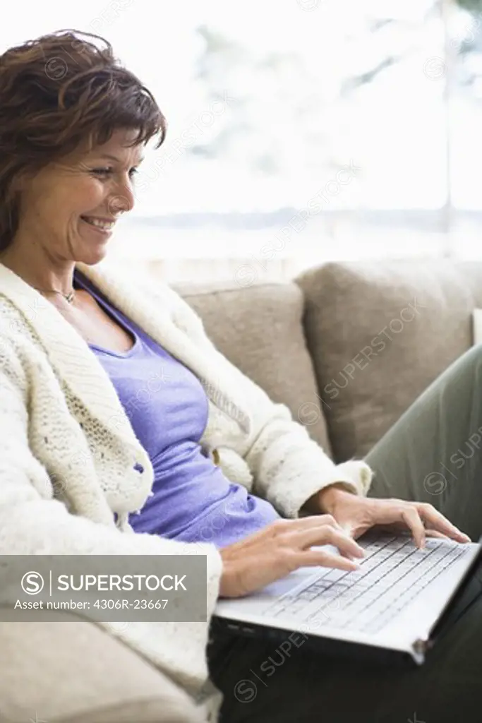 Woman sitting on sofa and surfing internet