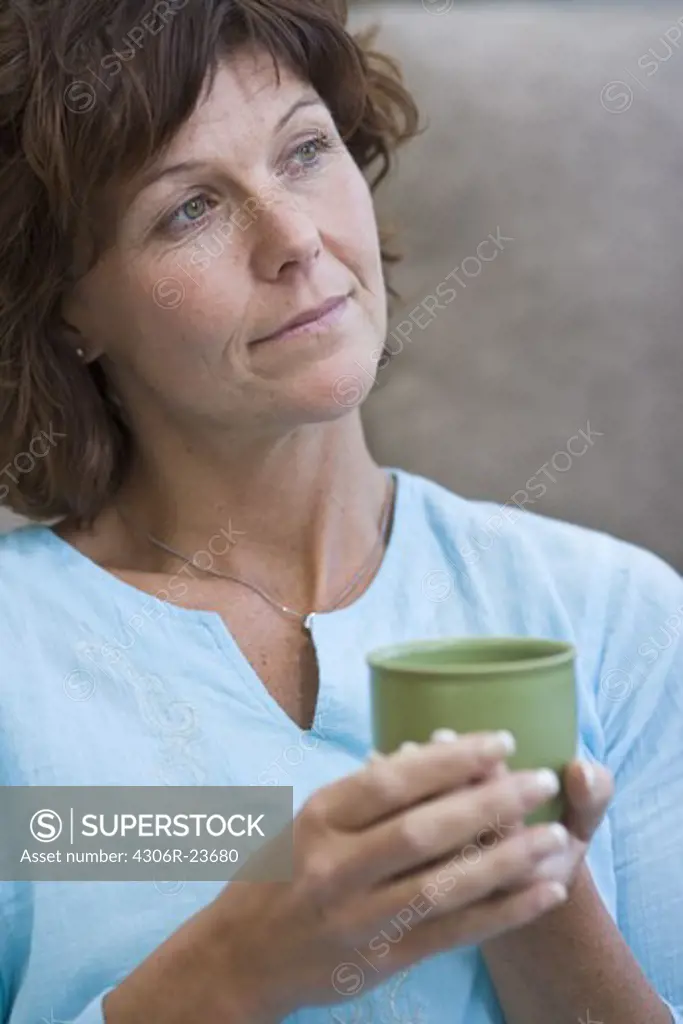 Mature woman holding cup, smiling