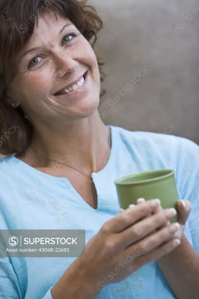 Mature woman holding cup, smiling
