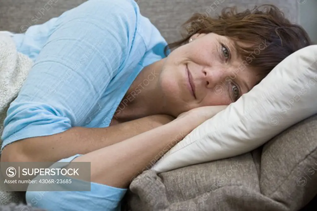 Mature woman lying on sofa, portrait