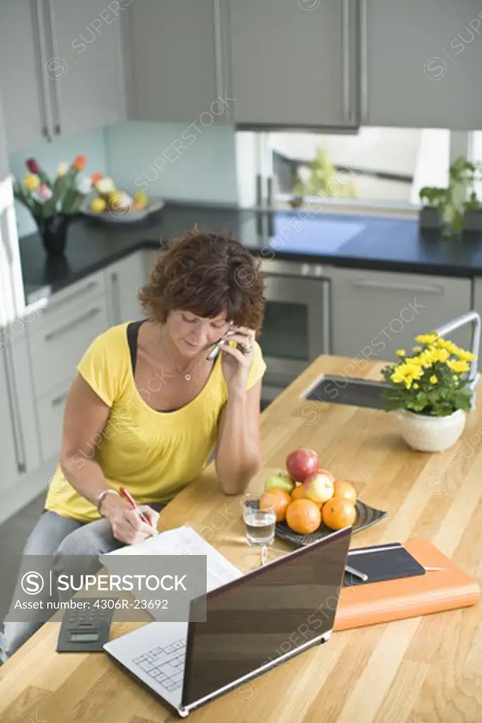 Woman sitting with bills and talking on mobile phone