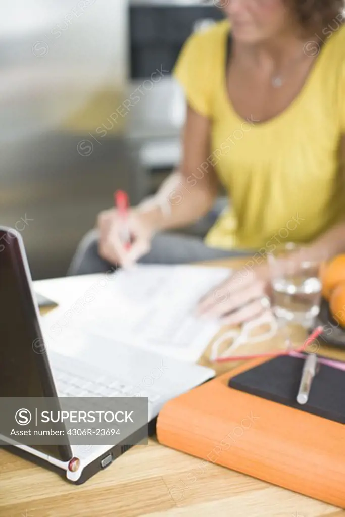 Woman sitting with bills and laptop