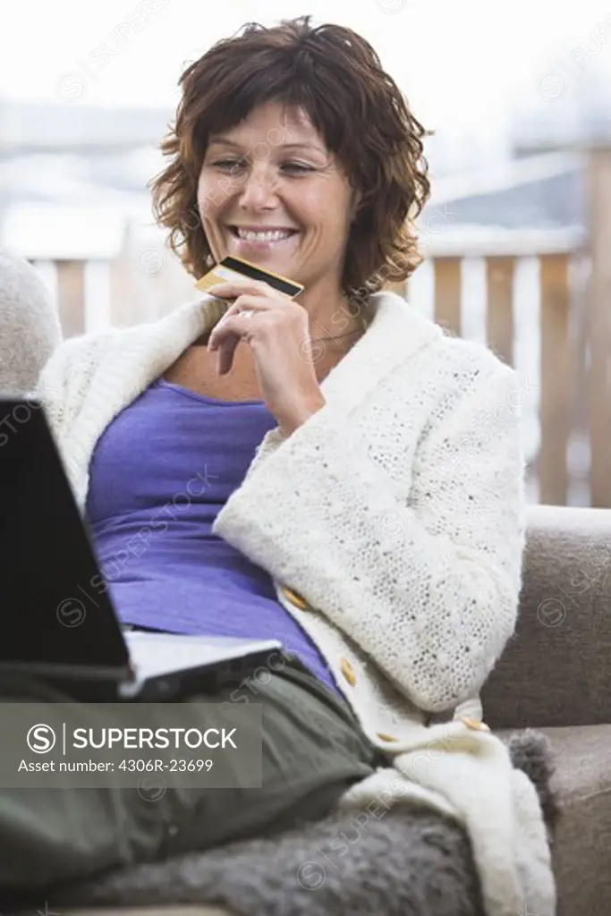 Woman holding credit card and using laptop