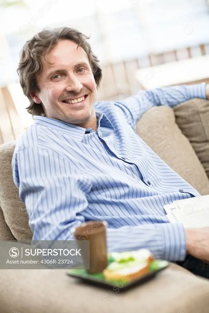 Portrait of cheerful mid-adult man sitting on sofa