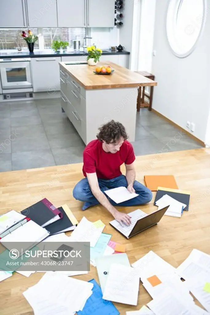 Elevated view of mid- adult man struggling with domestic paperwork