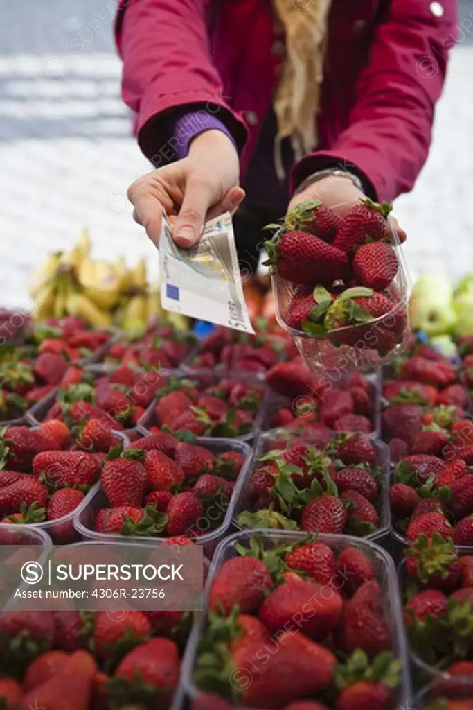 Close-up mid section of woman paying for basket of strawberries