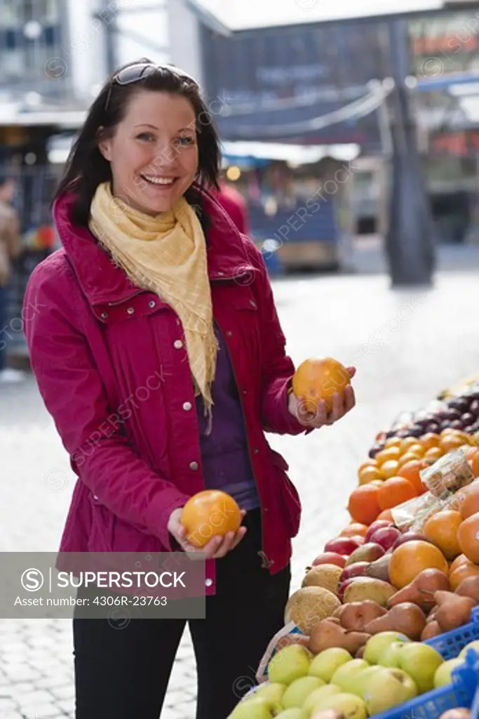Young woman choosing oranges at fruit market