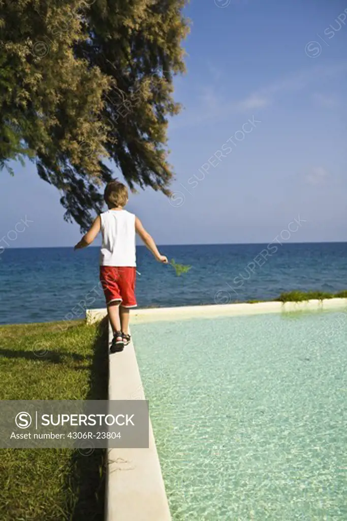 Boy walking on edge of pool
