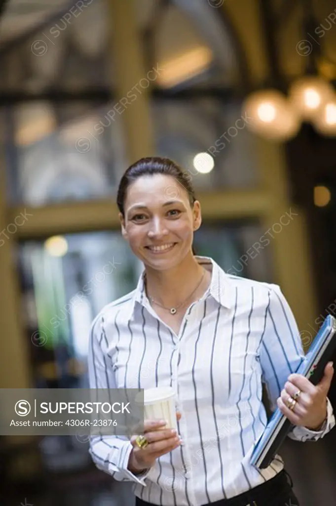 Portrait of businesswoman holding takeaway coffee in one hand and laptop in another