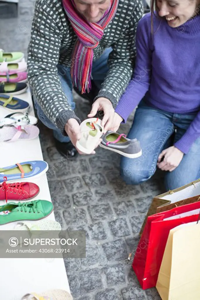 Couple observing shoes at outdoor market stall