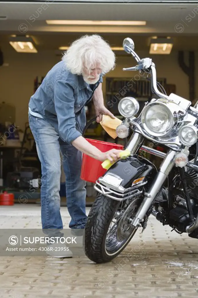 Man cleaning vintage motorbike in driveway