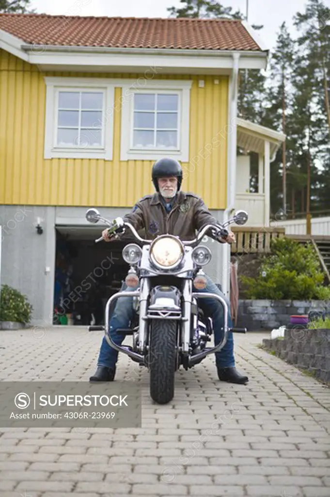 Man on vintage motorbike in driveway