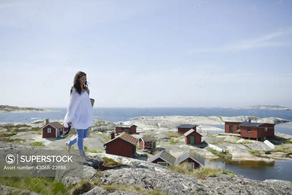 Woman walking on rock, houses in background