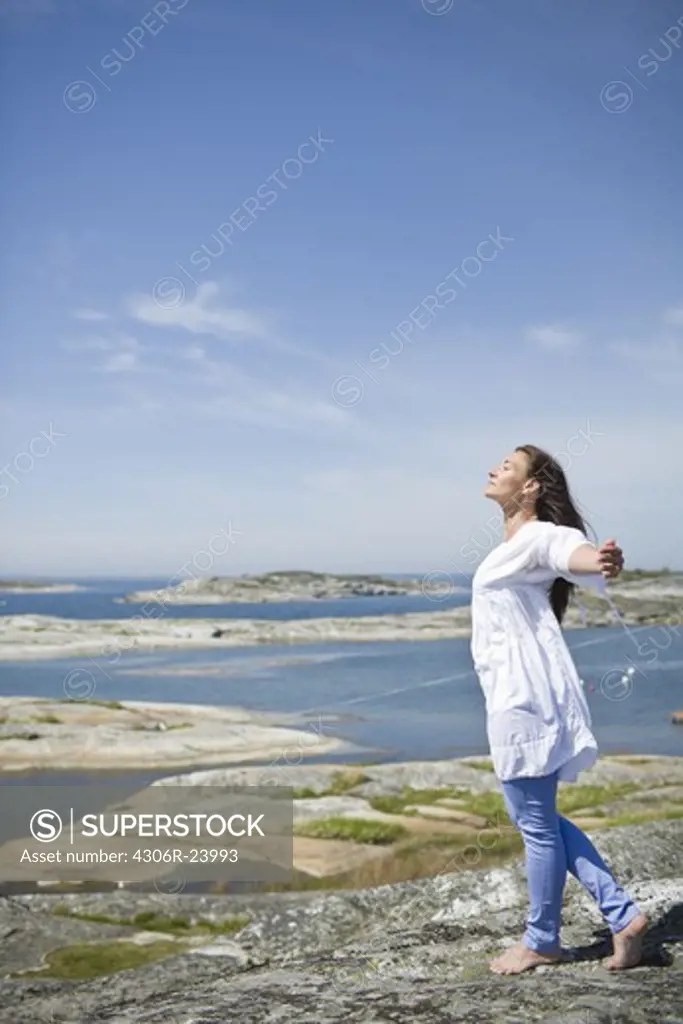 Woman standing on rock with arms up
