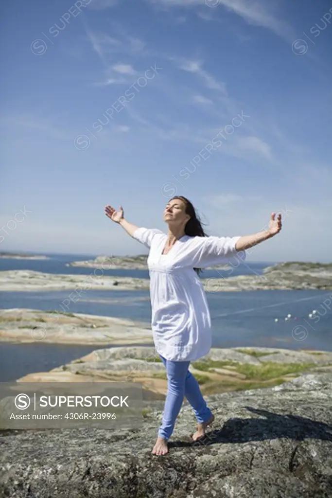 Woman walking on rock with arms up