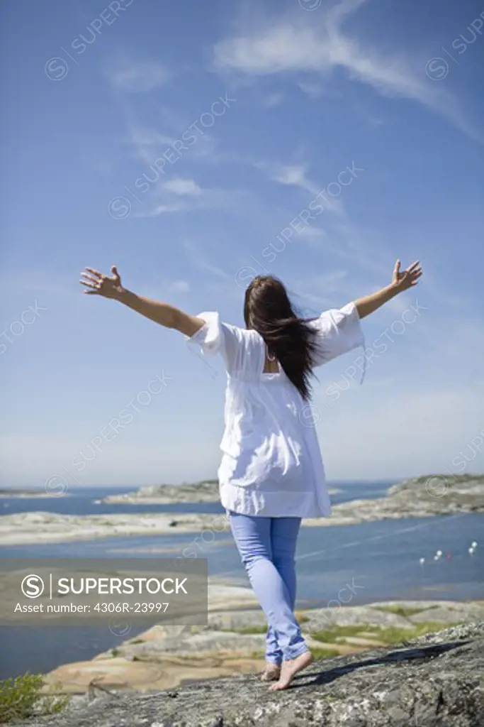 Woman standing on rock with arms up