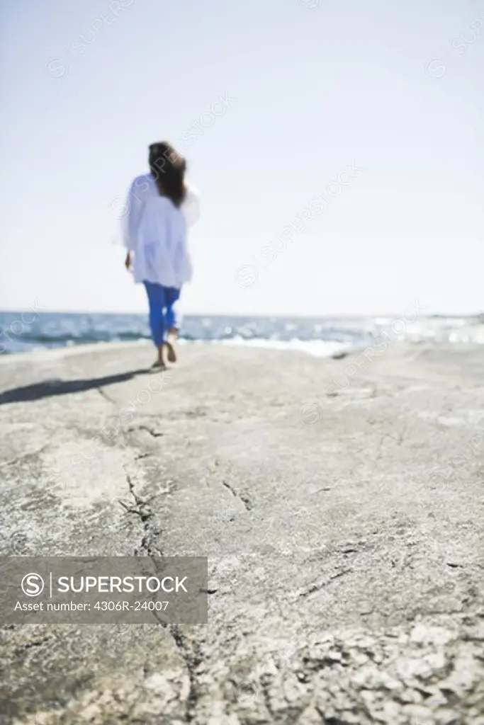 Woman walking on rock by sea