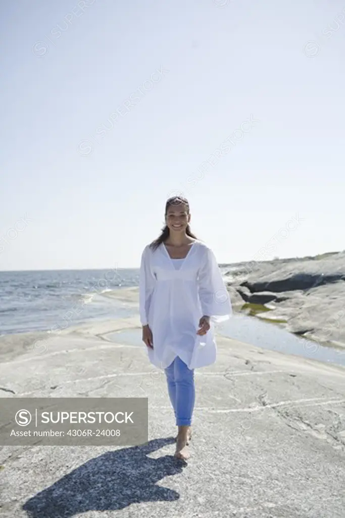 Woman walking on cliff next to sea