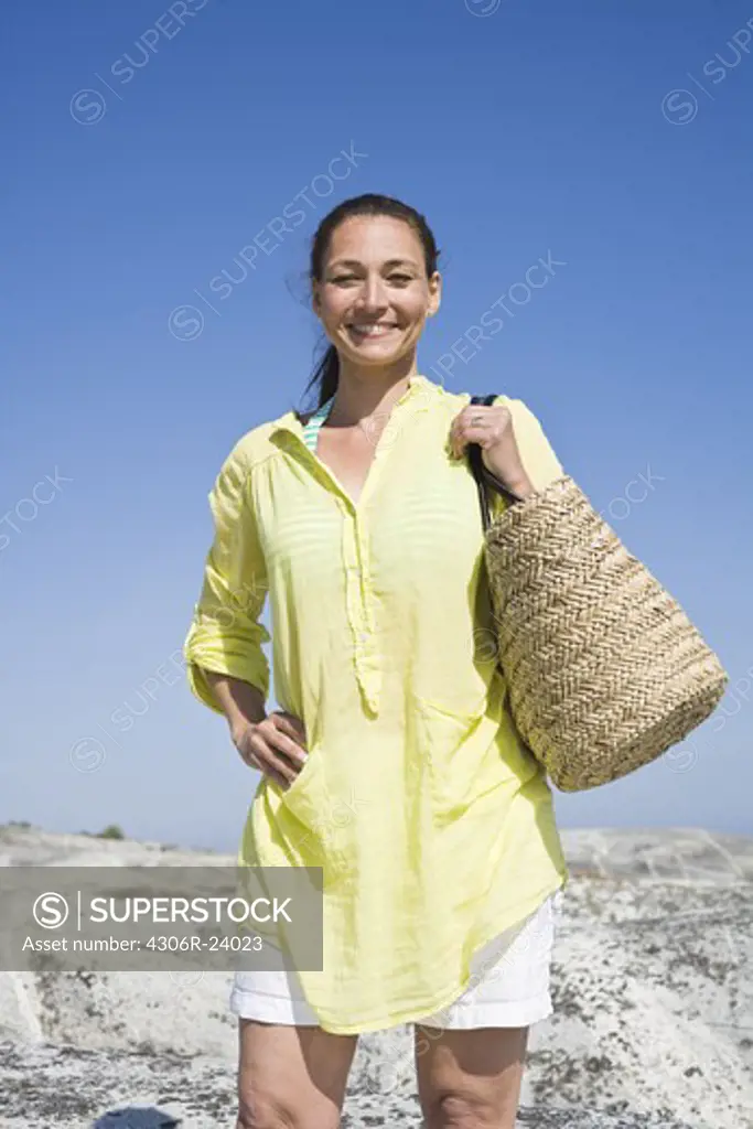 Woman with beach bag smiling, portrait