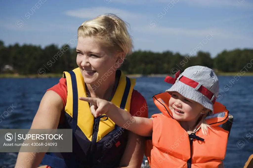 Mother and daughter driving a motorboat, Sweden.
