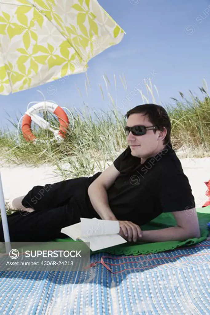 Man relaxing on beach wearing sunglasses
