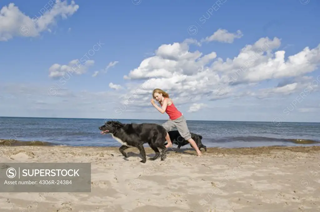 Girl with dogs running on beach