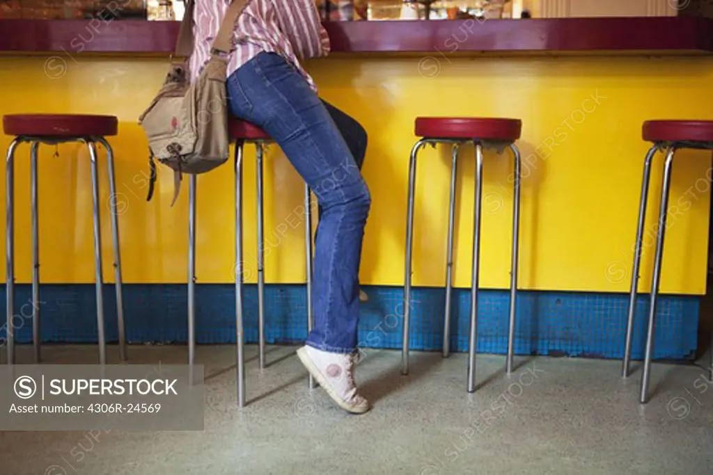 Legs of woman sitting at bar counter