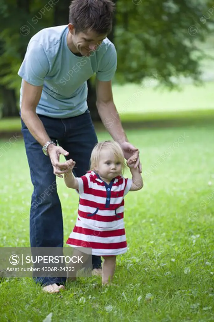 Mid adult father helping daughter with first steps